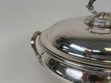 a silver plate with a lid on a white table