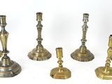 several brass candlesticks are lined up on a white surface