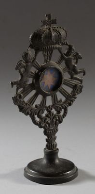 une petite horloge posée sur un socle et surmontée d'une couronne