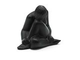 sculpture noire représentant une femme assise sur un oreiller posé sur une surface blanche