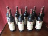 six bottles of wine are lined up on a wooden table