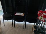 quatre chaises noires dans une pièce où se trouve un panneau « Stop »