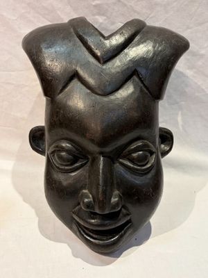 une image représentant une sculpture noire représentant le visage d'un homme sur fond blanc