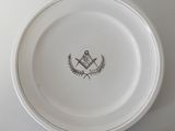 une assiette blanche ornée d'un emblème maçonnique