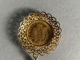 a close up of a gold necklace with a coin on it