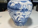 un vase bleu et blanc posé sur une table devant une bibliothèque