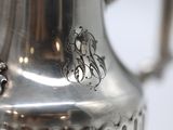 a silver coffee pot with a handle on a table