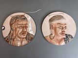 une paire de portraits en céramique représentant un homme et une femme, accrochés au mur