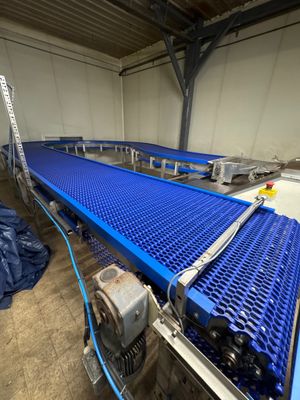 un tapis roulant bleu dans un entrepôt, recouvert d'une bâche bleue