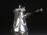 une cafetière ancienne en argent avec une anse, sur fond noir