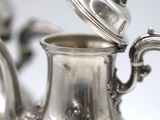 a silver tea pot with a lid on a table