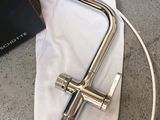a silver faucet on a white cloth next to a laptop