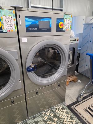 Plusieurs machines à laver sont alignées les unes à côté des autres dans une buanderie
