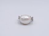 a close up of a white pearl and diamond ring on a white surface