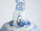 a blue and white vase with a dog on top of it