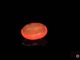une image représentant une pierre orange lumineuse posée sur une surface noire