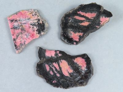 trois morceaux de roche rose et noire posés sur une surface blanche