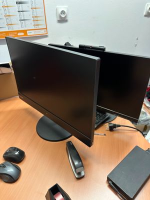 deux écrans posés sur un bureau, avec une souris et un téléphone portable