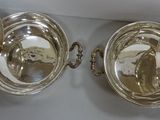 two silver dishes hanging on the wall next to each other