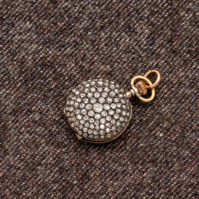 un gros plan sur un pendentif Locke en or et diamants, muni d'une chaîne