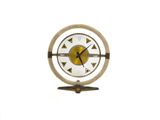 une horloge posée sur un support sur une surface blanche