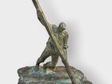 bronze statue of a baseball player holding a bat on a rock