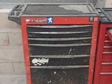 une boîte à outils rouge posée par terre à côté d'une autre boîte à outils rouge