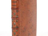 an old book with a brown cover sitting on top of a white surface