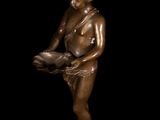 bronze statue of a boy holding a bowl on a black background