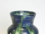 a blue and green vase sitting on a white surface