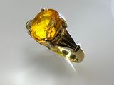 an image of a ring with a yellow stone on a white surface