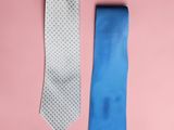 two ties on a pink surface one is blue and the other is white