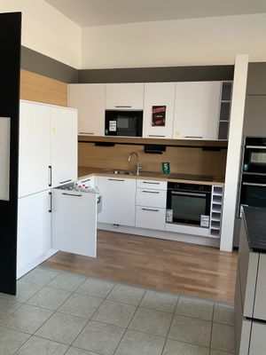 une photo d'une cuisine avec des placards blancs et des plans de travail noirs