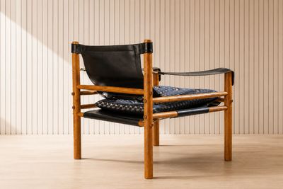 La chaise est en bois et son assise est en cuir noir.