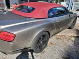 une voiture argentée au toit rouge garée devant un immeuble