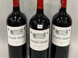 trois bouteilles de vin rouge sont alignées sur une surface blanche