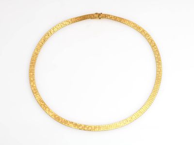 gros plan d'un collier en or sur une surface blanche