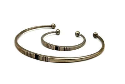 two silver bracelets with black stones on them on a white background