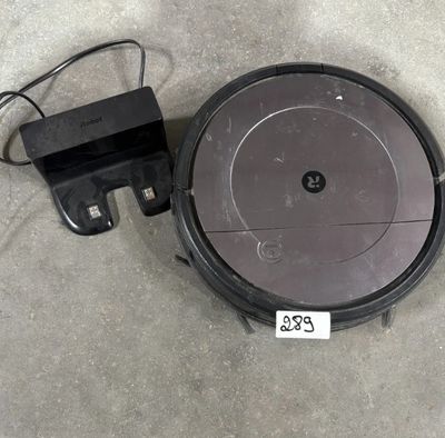 un gros plan d'un robot aspirateur posé sur le sol, avec son chargeur