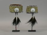two lamps with black and white feathers on them on a stand