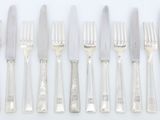 cinq fourchettes et un couteau sur une table blanche