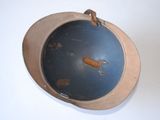 a metal bowl with a wooden handle on a white table