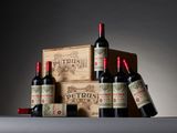 trois bouteilles de vin rouge sont posées devant une caisse en bois