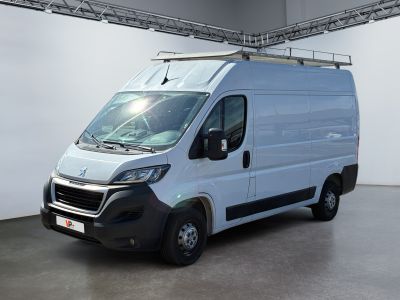 La camionnette blanche est garée dans une grande pièce équipée d'une galerie de toit.