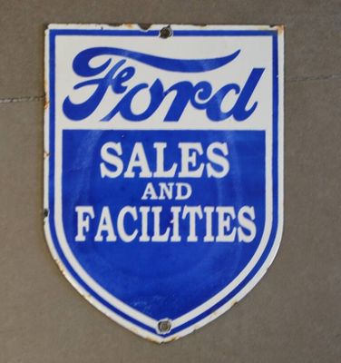 une enseigne bleue et blanche portant l'inscription « Ford Sales and Facilities » sur le côté d'un bâtiment
