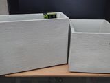 two white planters sitting on top of a wooden table
