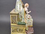 an antique figurine of a woman and child sitting on a bench