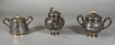 trois théières en argent et un sucrier posés sur une table