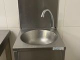 un lavabo en inox dans une salle de bains, équipé d'un robinet en métal