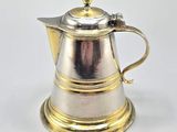 an antique silver and gold coffee pot sitting on top of a white table